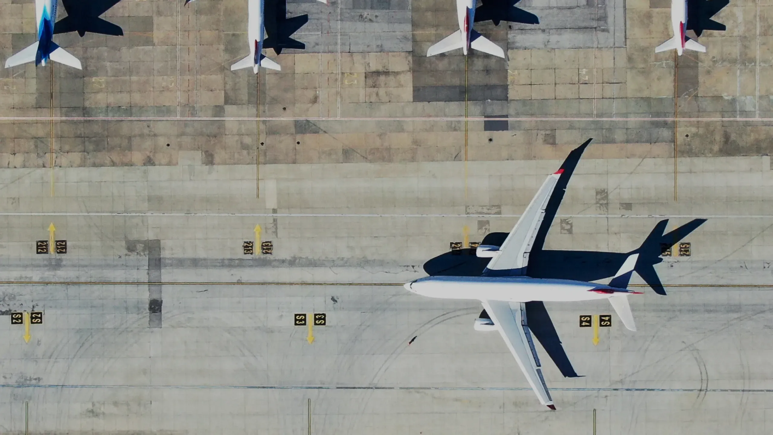 An aerial view of an airliner on an airport apron, with other aircraft parked at gates above it