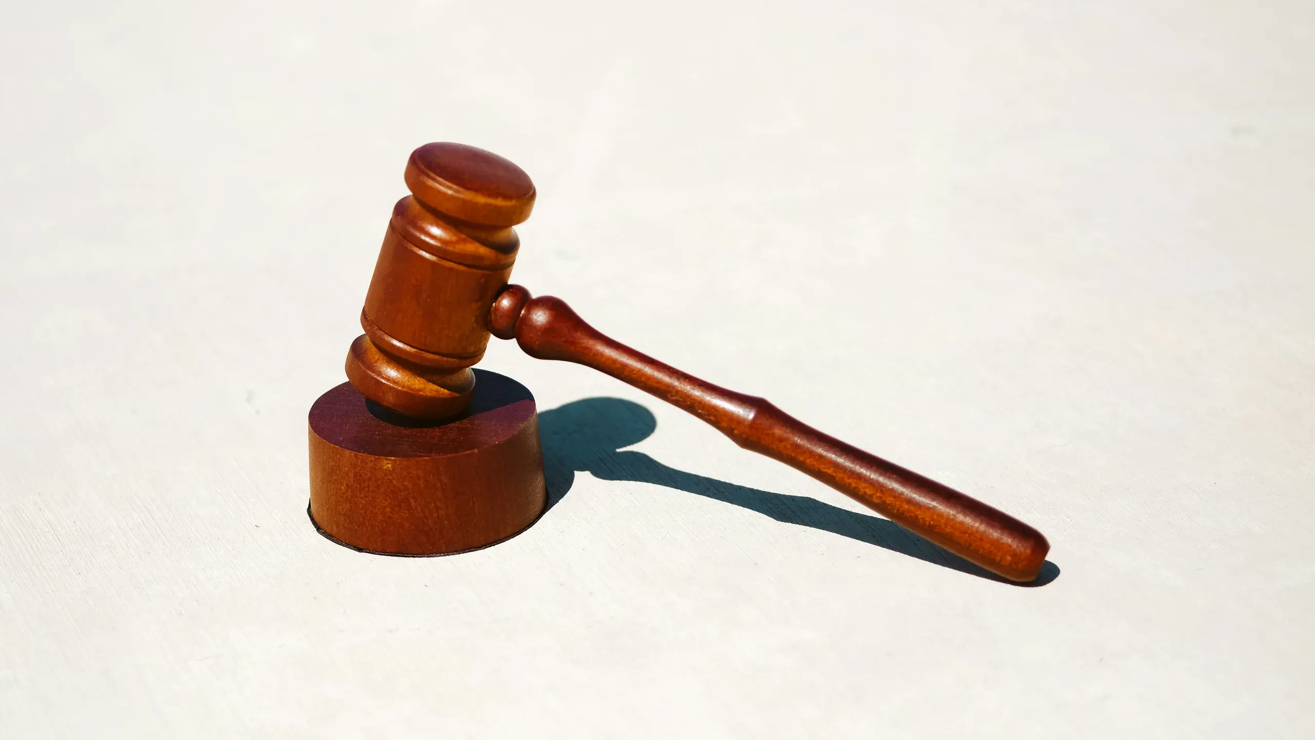 A wooden gavel resting on its block on a pale surface