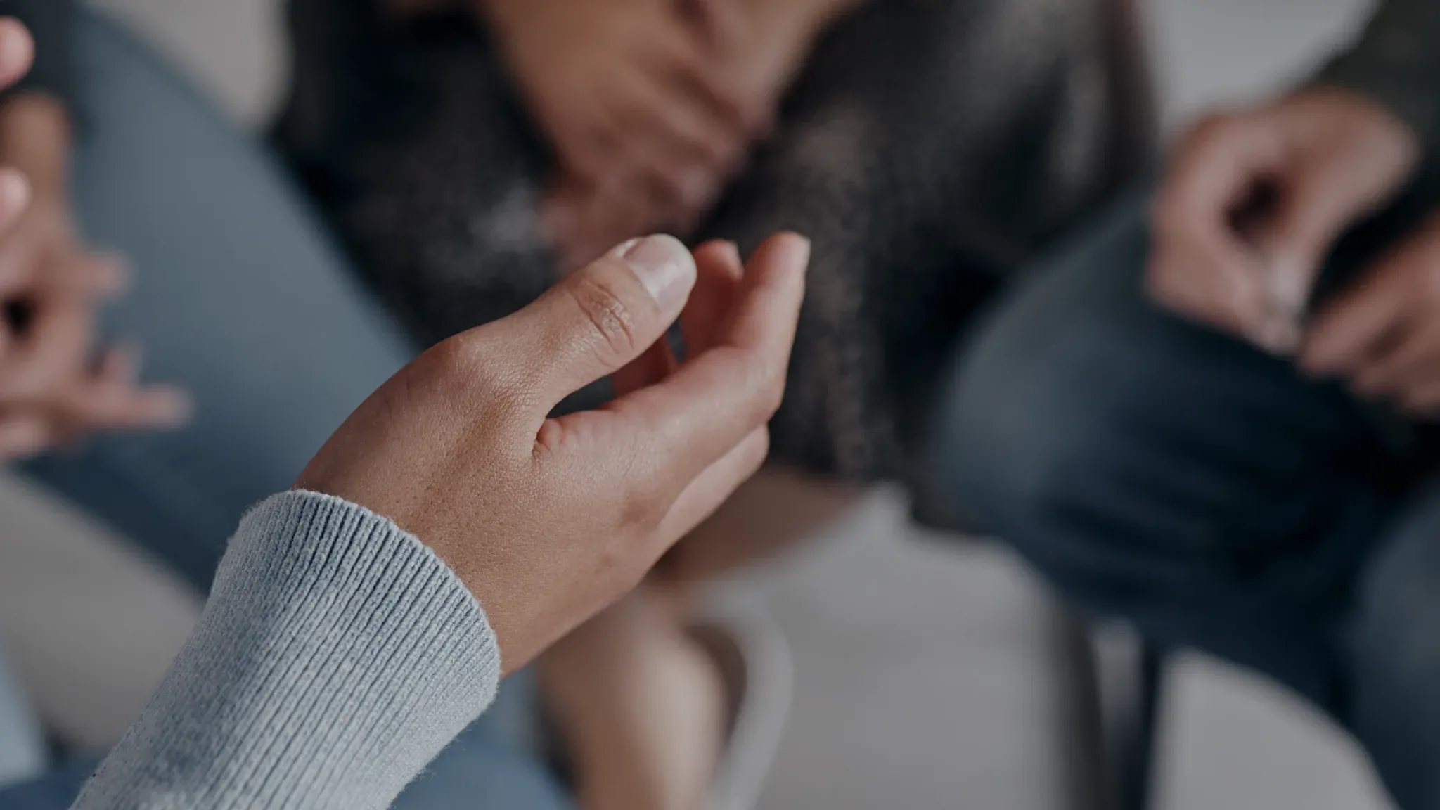 Two people sitting together, one resting a hand on the other’s arm.
